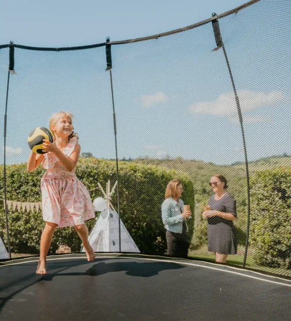 Dívka skáče a raduje se na trampolíně Springfree a jeho rodina jej u toho sleduje